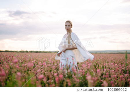 Beauty romantic girl Outdoors at sunset. Young woman in stylish clothes posing in the blooming field. Beauty romantic girl Outdoors at sunset. Young woman in stylish clothes posing in the blooming field. 102866012
