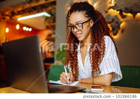 Portrait of African American woman sitting at cafe having video call on laptop computer. Portrait of African American woman sitting at cafe having video call on laptop computer. 102866186