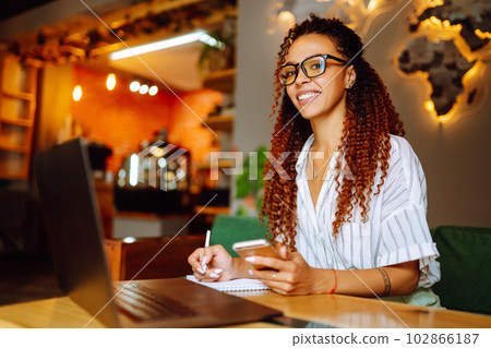 Portrait of African American woman sitting at cafe having video call on laptop computer. 102866187