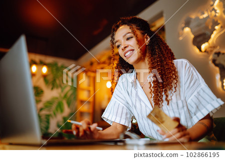 Young woman sitting at cafe making online shopping, using credit card and laptop. Online shopping Young woman sitting at cafe making online shopping, using credit card and laptop. Online shopping 102866195