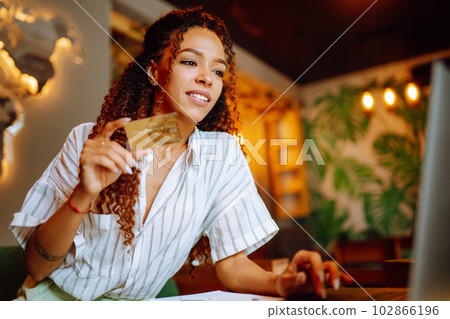 Young woman sitting at cafe making online shopping, using credit card and laptop. Online shopping Young woman sitting at cafe making online shopping, using credit card and laptop. Online shopping 102866196