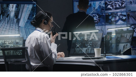 Female officer works on computer with CCTV cameras footage 102866301
