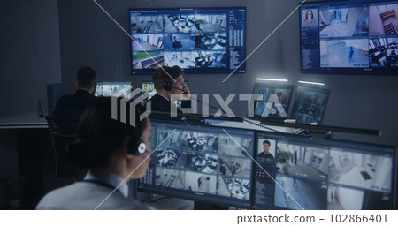 Female security officer watches security cameras with male colleagues 102866401
