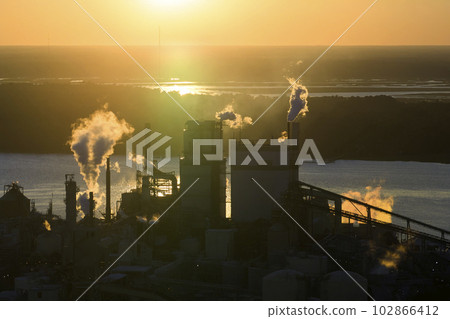 Aerial view of wood processing factory with smoke from production process polluting atmosphere at plant manufacturing yard. Industrial site at sunset 102866412