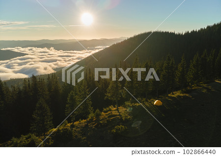 Aerial view of tourist camping tent on mountain campsite at bright sunny evening. Active tourism and hiking concept Aerial view of tourist camping tent on mountain campsite at bright sunny evening. Active tourism and hiking concept 102866440