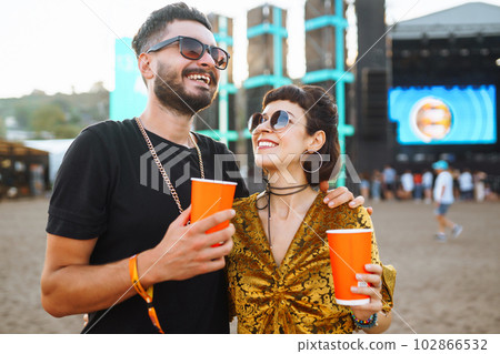 Lovely couple having fun at festival. Young friends with beer at beach party. Summer holiday, vacation. Lovely couple having fun at festival. Young friends with beer at beach party. Summer holiday, vacation. 102866532