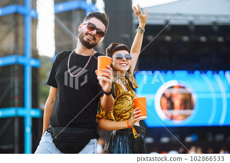 Lovely couple having fun at festival. Young friends with beer at beach party. Summer holiday, vacation. Lovely couple having fun at festival. Young friends with beer at beach party. Summer holiday, vacation. 102866533
