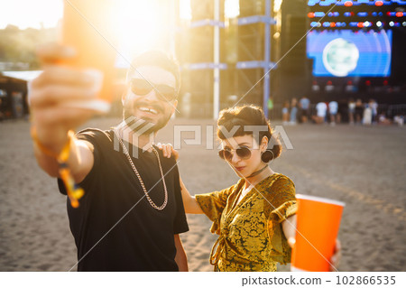 Lovely couple having fun at festival. Young friends with beer at beach party. Summer holiday, vacation. Lovely couple having fun at festival. Young friends with beer at beach party. Summer holiday, vacation. 102866535