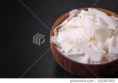 White dry coconut flakes in a wooden bowl prepared for making desserts 102867002
