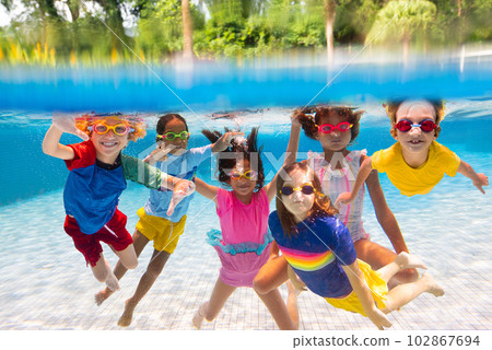 Kids jump into swimming pool. Summer water fun. Kids jump into swimming pool. Summer water fun. 102867694