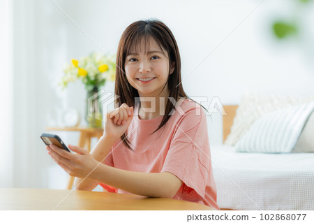 A woman looking at her smartphone in the living room A woman looking at her smartphone in the living room 102868077