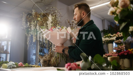 Concentrated male florist wraps flowers bouquet Concentrated male florist wraps flowers bouquet 102868503