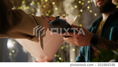 Woman buys flowers and pays with contactless payment using smartphone Woman buys flowers and pays with contactless payment using smartphone 102868586