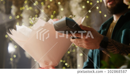 Woman buys flowers and pays with contactless payment using smartphone Woman buys flowers and pays with contactless payment using smartphone 102868587