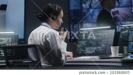 Female officer works on computer with CCTV cameras footage Female officer works on computer with CCTV cameras footage 102868605