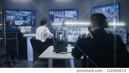 Diverse team of officers watch CCTV cameras in security control center Diverse team of officers watch CCTV cameras in security control center 102868619