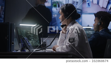 Female officer works on computer in police monitoring center 102868674
