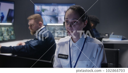 Female security operator in headset looks at screen Female security operator in headset looks at screen 102868703