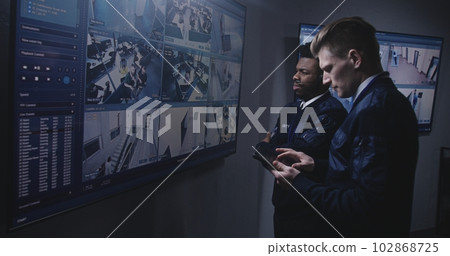 Officer monitors cameras and talks with colleague 102868725