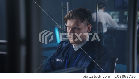 Male security officer in headset talks, controls CCTV cameras on PC Male security officer in headset talks, controls CCTV cameras on PC 102868736