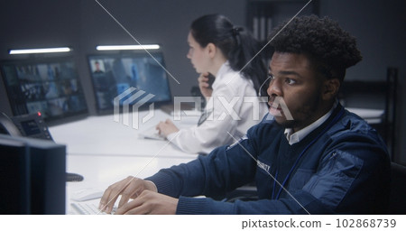 Security operator types keyboard and looks at monitor 102868739