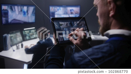 Security officer zoom CCTV cameras uses tablet 102868770