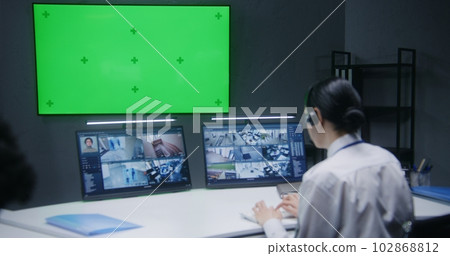 Female officer controls CCTV cameras in security control center 102868812