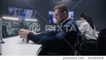 Security officer touches tablet and controls CCTV cameras 102868816