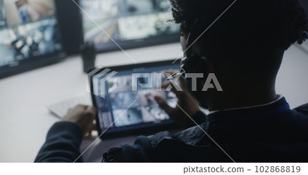 African American operator monitors CCTV cameras on tablet 102868819
