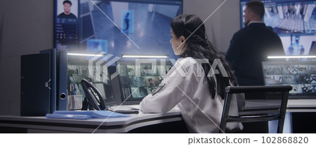 Female officer works on computer in police monitoring center 102868820