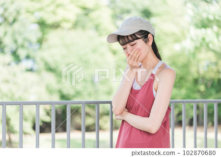 Asian woman in sportswear who is troubled by nausea and dizziness during exercise 102870680