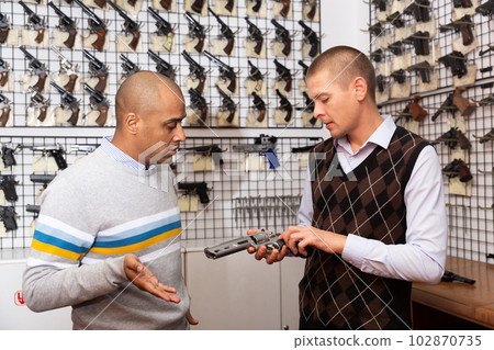 Two men choosing sporting and hunting revolvers in gunsmith shop 102870735
