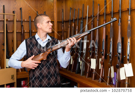 Buyer selects combat rifle at a gun store Buyer selects combat rifle at a gun store 102870758