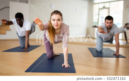 Woman practicing Dandayamna Bharmanasana during group yoga training 102871162