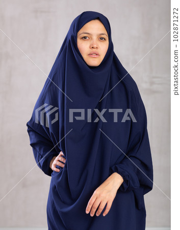 Portrait of young positive woman in khimara posing in studio 102871272