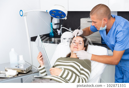 Cosmetologist examining female client face before procedure 102871331