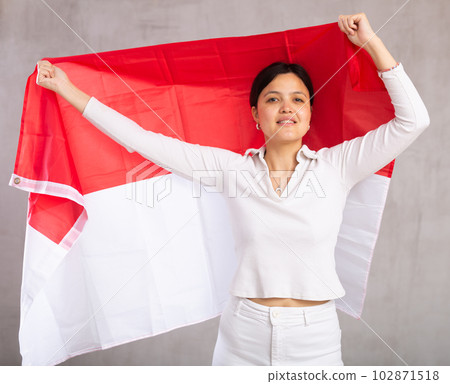Middle-aged positive woman in casual clothes hold unfurled flag of Monaco in hands raised above head Middle-aged positive woman in casual clothes hold unfurled flag of Monaco in hands raised above head 102871518