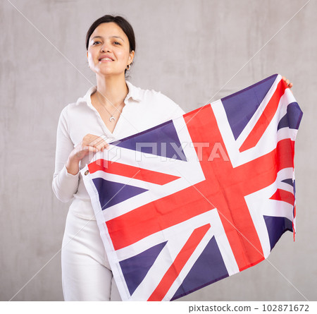 Reliant young woman holds big national British flag with confident smile showing teeth 102871672