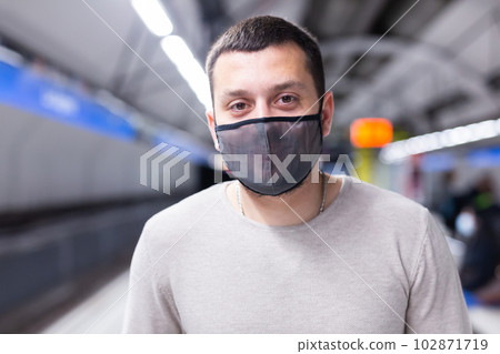 Young man in mask walking through underground station 102871719