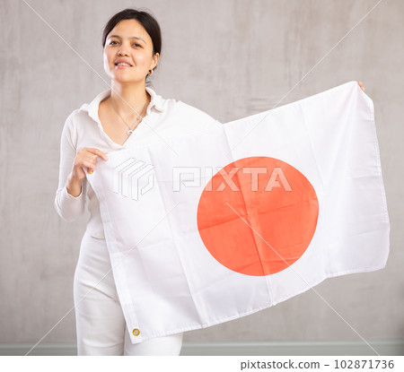 Reliant positive young woman holds big national flag of Japan with confident smile showing teeth 102871736