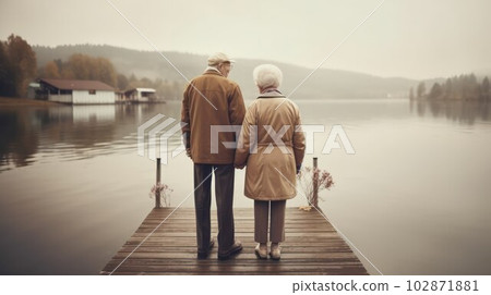 elderly gray-haired couple man and woman walking on the shore of the lake.  102871881
