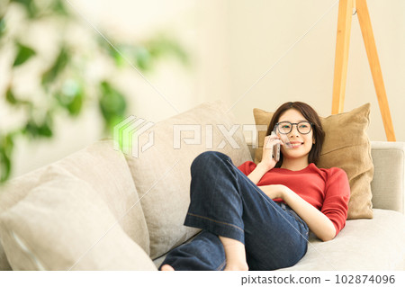 Young woman in plain clothes, living room, smartphone Young woman in plain clothes, living room, smartphone 102874096