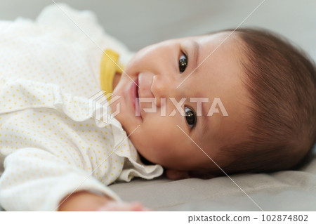 happy infant baby smilling while lying on bed happy infant baby smilling while lying on bed 102874802