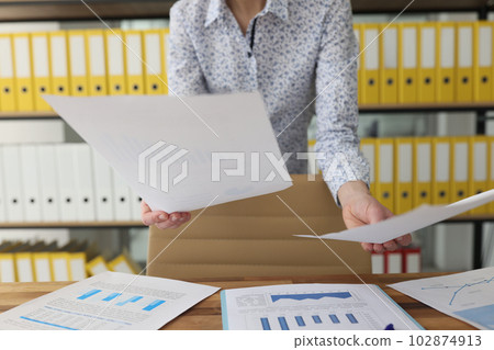 Woman worker sorts accounting documents standing at table Woman worker sorts accounting documents standing at table 102874913