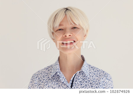 Positive blonde female smiles while standing in bright room 102874926