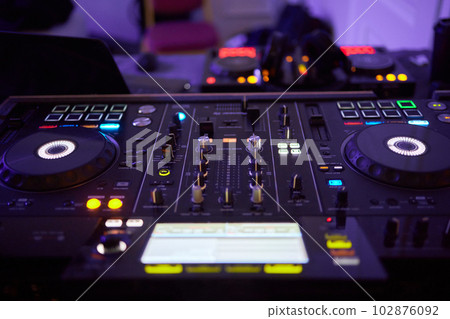 DJ console cd mp4 deejay mixing desk Ibiza house techno dance music wedding reception party in nightclub with colored lighting effect disco lights. 102876092