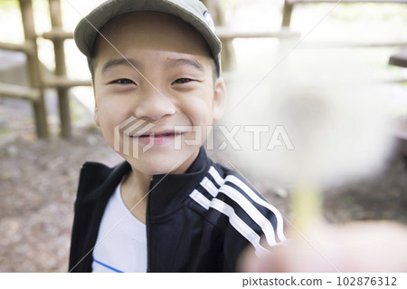 Outdoor image A boy holds out a dandelion fluff Outdoor image A boy holds out a dandelion fluff 102876312