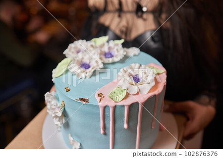 Female baker holding a delicious cake. Chef holding freshly made cake. 102876376