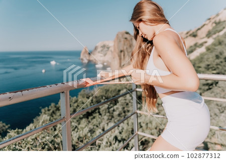 Woman sea fitness. Happy woman with long hair, fitness instructor in white doing stretching and pilates with ribbons in park near the sea. Female fitness yoga routine concept. Healthy lifestyle. Woman sea fitness. Happy woman with long hair, fitness instructor in white doing stretching and pilates with ribbons in park near the sea. Female fitness yoga routine concept. Healthy lifestyle. 102877312