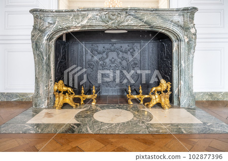 Old marble fireplace with golden forging. Chateau Versailles near Paris, France 102877396